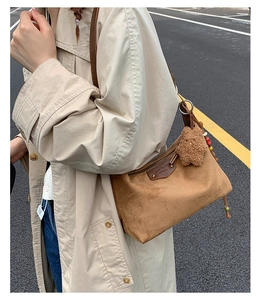 Sac hobo en daim marron avec pendentif ours porté par un mannequin en rue