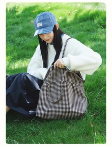 Detail shot of houndstooth tote bag texture and spacious interior on a green lawn