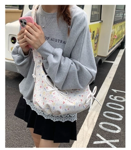 Détail d'un sac bandoulière blanc à fleurs avec nœud latéral et sangle en coton