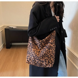 Detailed view of large leopard print tote bag styled with casual black coat and jeans