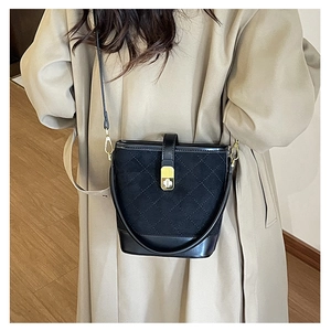 Close-up of black quilted bucket bag in suede and leather with gold twist lock hardware