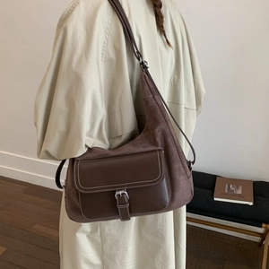 Detail of brown suede and leather crossbody bag with silver buckle and white stitching