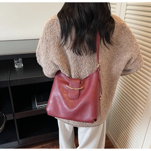 Close-up of textured burgundy leather tote bag with elegant gold curved metal buckle