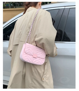 Detail einer rosa gesteppten Schultertasche mit V-Naht und Kettenriemen am Modell