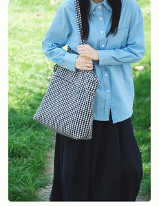 Close-up of houndstooth tote bag texture and design on a stylish casual outfit