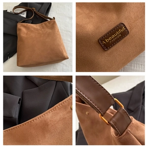 Detail view of brown suede tote bag showing logo patch, stitching and gold hardware