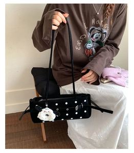 Detail of black polka dot suede shoulder bag with metal studs and side buckle decoration