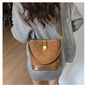Detail of vintage brown bucket bag with quilted stitching and gold clasp shown on model