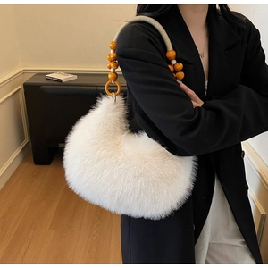 Detail of white fluffy faux fur handbag featuring orange wooden beaded handle and rings