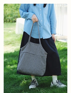 Detailed close-up of a large black and white houndstooth knit tote bag in outdoor lighting