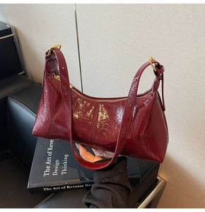 Détail du sac à main rouge vin en cuir verni plissé avec des finitions dorées