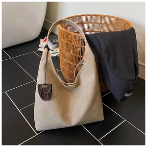 Detail view of khaki tote bag with matte texture and leopard heart pendant