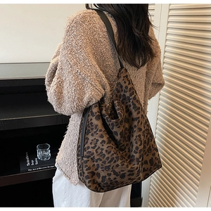 Detail of leopard print hobo bag with wide shoulder strap worn by a model in a room