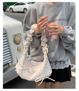 Détail du sac hobo plissé à fleurs avec nœuds délicats et bandoulière à volants