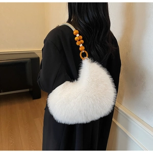 Detailed back view of a white fuzzy crescent bag with orange beaded shoulder strap
