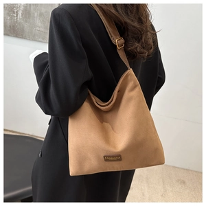 Rear view of a model wearing a brown frosted suede tote bag with adjustable shoulder strap
