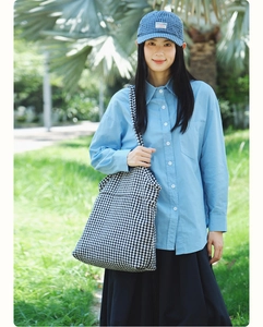 Houndstooth canvas tote bag with blue shirt and baseball cap in a park setting
