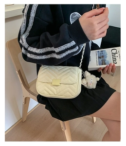 Detail der cremefarbenen Stepptasche mit Goldkette und Plüsch-Hasenanhänger