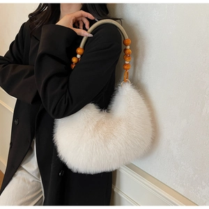 Close-up of white faux fur hobo bag with ethnic wooden bead handle and soft texture