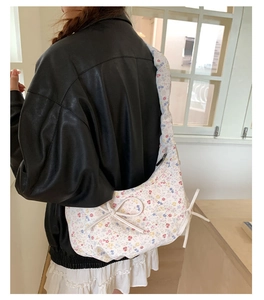 Gros plan d'un sac bandoulière en toile fleurie avec nœud sur un mannequin