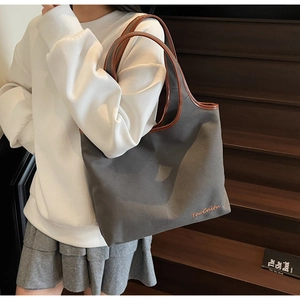 Detail view of large canvas tote bag with brown leather trim and TaoCaitu logo