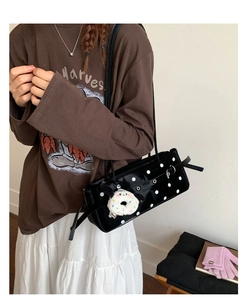 Detail of vintage polka dot handbag with plush donut charm and shiny patent finish