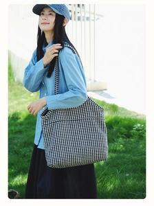 Outdoor shot of a black and white houndstooth tote bag worn by a model in nature