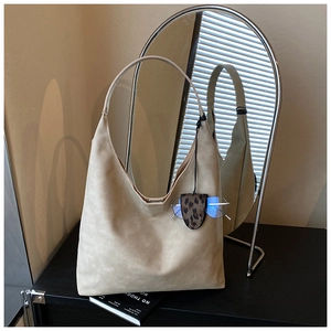 Detail view of beige matte leather tote bag with thin straps and leopard print charm