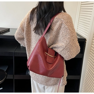 Detail of dark red hobo bag showing high-quality leather texture and gold metal clasp
