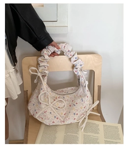Sac hobo fleuri avec poignée nouée et nœuds décoratifs sur une chaise en bois