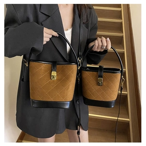 Close-up of brown suede bucket bags with diamond stitching and black leather trim