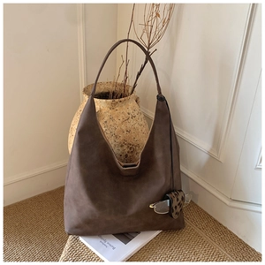 Close-up of brown suede hobo bag with a leopard print charm used as glasses holder