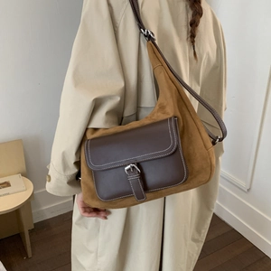 Detail of vintage brown suede crossbody bag featuring leather flap pocket and silver buckle