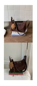Détail macro du sac hobo en daim marron avec bandoulière cuir et breloque ours en peluche