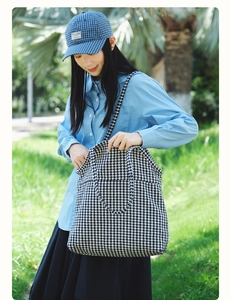 Detailed outdoor shot of a large houndstooth tote bag with dual straps on green grass