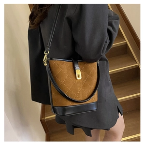Detail of vintage quilted bucket bag in brown suede and black trim with gold hardware