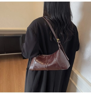 Detail of dark brown oil wax leather underarm bag with gold buckle and adjustable strap