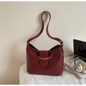 Close-up of a burgundy leather shoulder bag featuring elegant golden crescent hardware detail