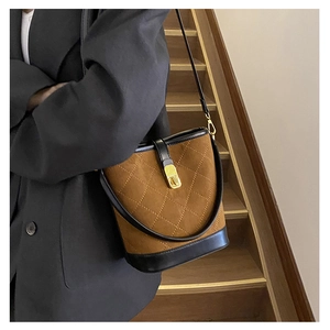 Detail of vintage quilted bucket bag with matte brown suede and gold metal lock