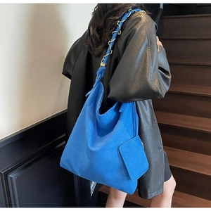 Détail du sac seau en daim bleu cobalt avec bandoulière chaîne et mini pochette
