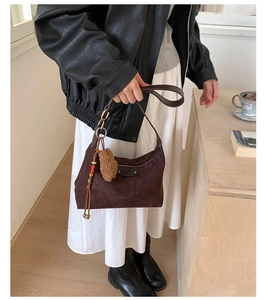 Détail du sac hobo en daim marron foncé avec pompon en perles et décor intérieur doux