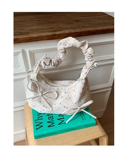 Détail du sac à fleurs avec poignées plissées et petits nœuds papillon sur le côté