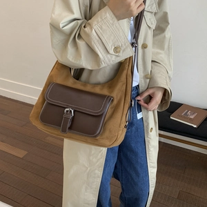 Detail showing retro brown suede crossbody bag with contrast stitching and metal buckle