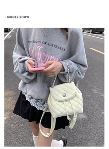 Dettaglio mini zaino trapuntato bianco con coulisse di perle e manico a catena su modella
