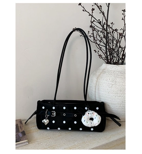 Detail of black polka dot underarm bag with silver heart charm and plush pendant