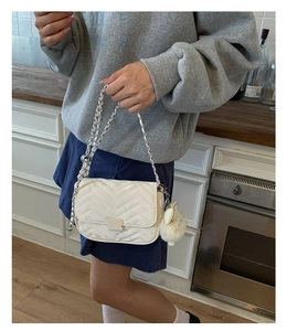 Details der weißen Stepptasche mit silberner Kette und Plüschtier-Anhänger für Damen