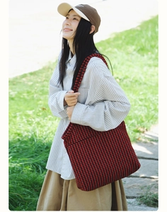 Outdoor view of a large houndstooth tote bag in red and black canvas worn by a model