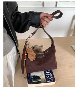 Détails du sac à bandoulière en daim marron foncé avec fermeture éclair dorée et breloque