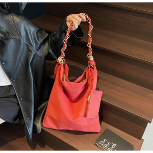 Détail du sac hobo en daim rouge avec chaîne dorée et petit porte-monnaie