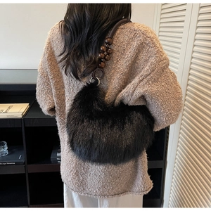 Detail of fuzzy black faux fur shoulder bag with wooden bead strap and knit sweater